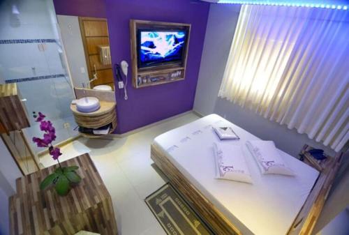 Habitación púrpura con cama y TV en Karinho Hotel en Santo André