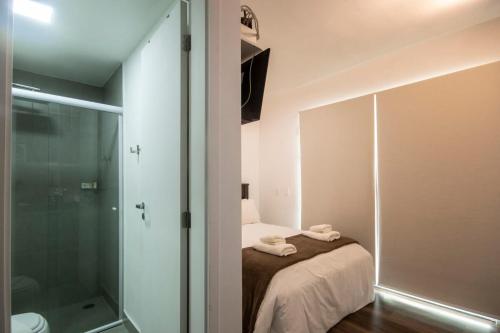 a bathroom with a bed and a glass shower at BHomy Turiassu in Sao Paulo