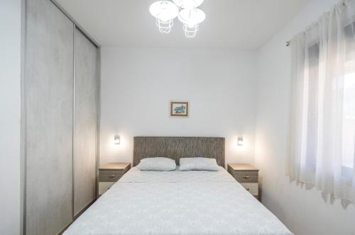 1 dormitorio con cama blanca y lámpara de araña en Apartments Milunović, en Kotor