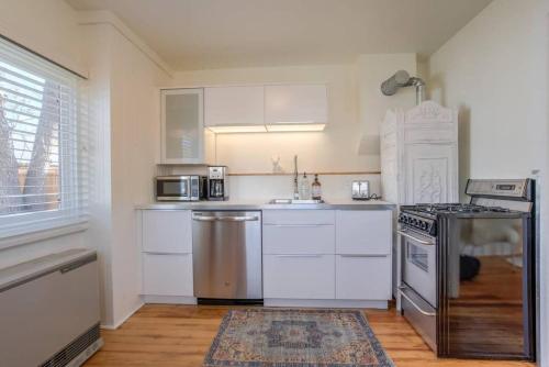 a kitchen with white cabinets and a stainless steel appliance at Vintage Tiny House CUTE 1BDRM Big Appeal in Colorado Springs