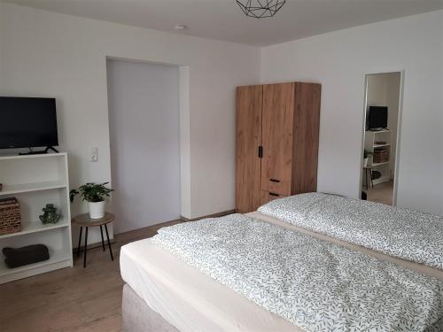 ein weißes Schlafzimmer mit 2 Betten und einem TV in der Unterkunft Ferienwohnung Alte Landstube in Hürtgenwald
