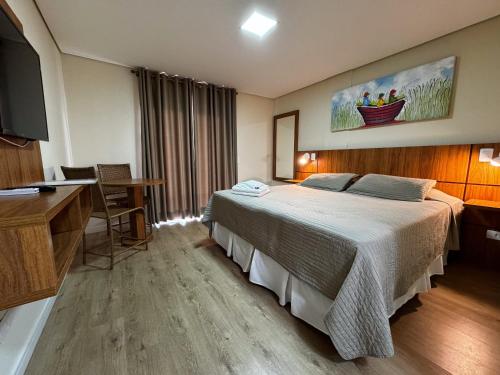 Habitación de hotel con cama y escritorio en Pousada Kaliman Luxo en Campos do Jordão