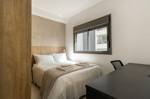 um quarto com uma cama, uma secretária e uma janela em BHomy Butanta - Para até 3 pessoas SM46 em São Paulo