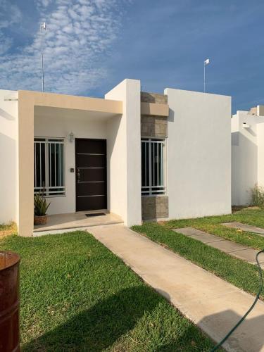 a white house with a garage and a driveway at Casa de Descanso y Aventuras en zona privada in Mérida