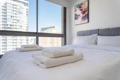 a white bedroom with two beds with towels on them at BHomy V Nova Conceicao - Suíte e varanda NX1409 in Sao Paulo