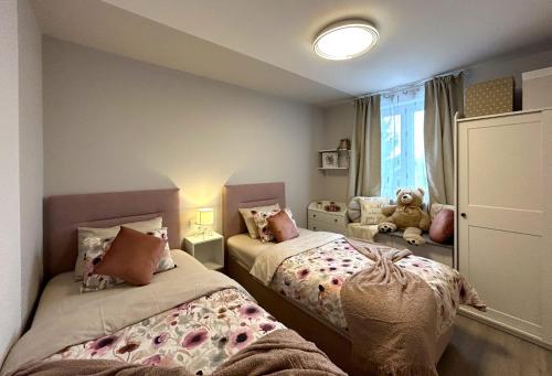 a bedroom with two beds and a teddy bear in a window at Apartment Aria in Lovran