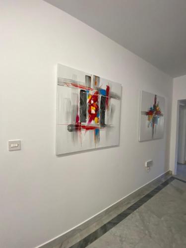 three paintings on a wall in a white room at XL Spacious Apartment, 4-BR Home in Central Area, WALK to Sliema - St Julian's in Il-Gżira