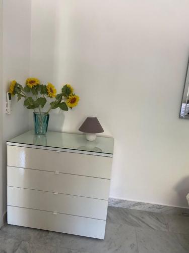 a dresser with a vase of flowers and a lamp at XL Spacious Apartment, 4-BR Home in Central Area, WALK to Sliema - St Julian's in Il-Gżira