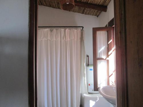 a bathroom with a white shower curtain and a sink at La Calabaza Cabaña in Tilcara