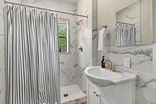a white bathroom with a shower curtain and a sink at Apt on Town Square - Ultimate DT Fay Location in Fayetteville