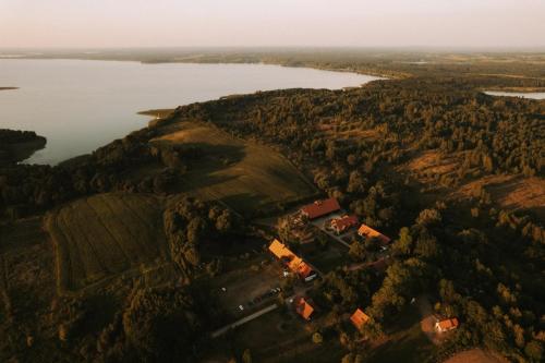eine Luftansicht eines Bauernhofs auf einem Hügel neben einem See in der Unterkunft Poganty - Jałownik in Giżycko