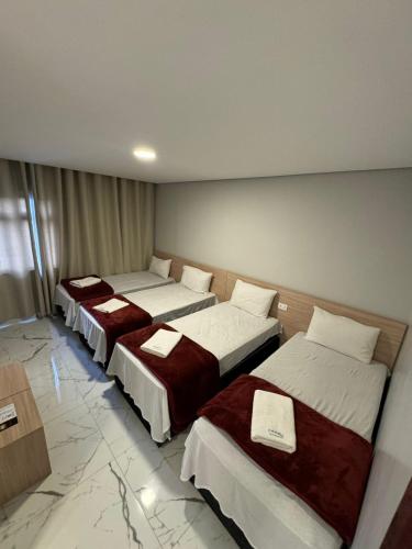 three beds in a room with marble floors at Hotel Fênix Belenzinho in Sao Paulo