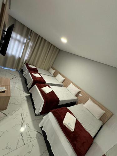 three beds in a room with marble floors at Hotel Fênix Belenzinho in Sao Paulo