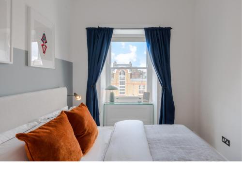 a bedroom with a bed with blue curtains and a window at The Highlife Holborn in London