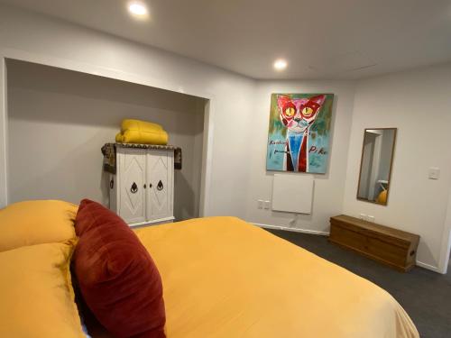 a bedroom with a yellow bed and a painting on the wall at Coastal Chic in Pohara in Pohara