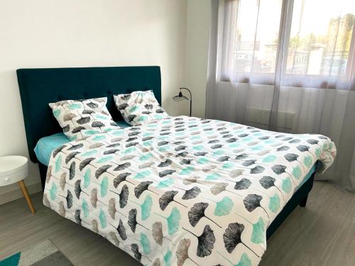 a bedroom with a bed with a comforter and a window at Appartement calme Antony, terrasse, vue jardin, proche Paris et Orly in Antony