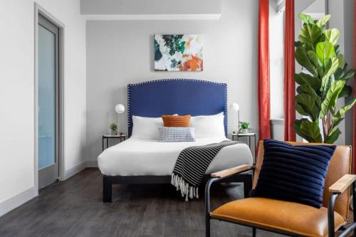 um quarto com uma cama com uma cabeceira azul e 2 cadeiras em Bright Studio Downtown 98 Walk Score em Cincinnati