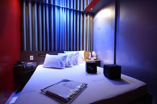 Schlafzimmer mit einem Bett mit weißer Bettwäsche und Kissen in der Unterkunft Hotel Karinho 2 in Santo André