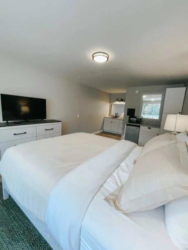 a bedroom with a large white bed and a flat screen tv at Hiker's Haven in Townsend