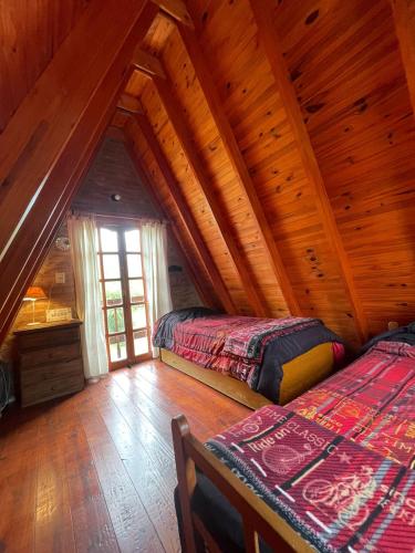 a bedroom with two beds in a wooden cabin at Cabaña Balcón Serrano in Cortaderas