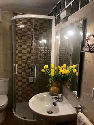 baño con lavabo y jarrón de flores amarillas en Elsoto en Quintana del Pidio