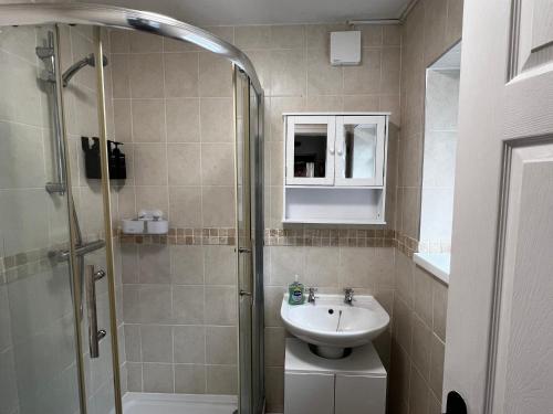 a bathroom with a sink and a shower at Robin’s Hollow: 2BD Home Near Wrexham AFC in Wrexham