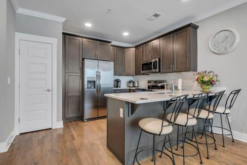a kitchen with wooden cabinets and a island with bar stools at Modern Nations Condo - Walkable - 5 Mi Downtown in Nashville