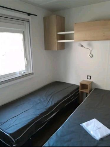 une petite chambre avec un lit et une fenêtre dans l'établissement Mobil home avec terrasse, à Piriac-sur-Mer