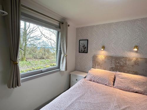 a bedroom with a bed and a window at Kilcoy Chalets in Muir of Ord