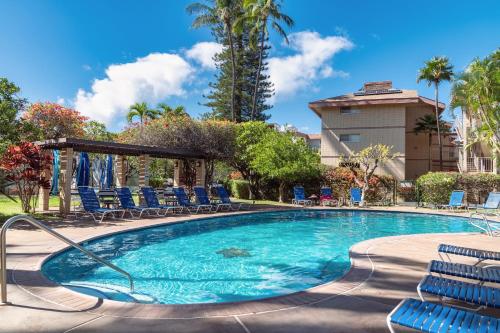 a swimming pool with chairs and trees and a building at B-204 Haleakala Shores in Wailea