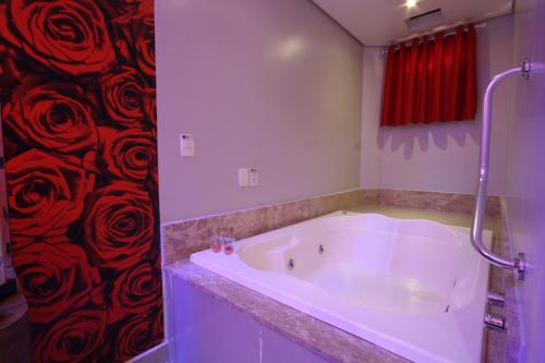 uma banheira na casa de banho com uma cortina de chuveiro vermelha em Karinho Hotel 4 em Santo André