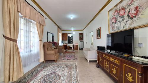 villa puncak bogor by GO puncak في Cikundul: غرفة معيشة مع تلفزيون بشاشة مسطحة كبيرة
