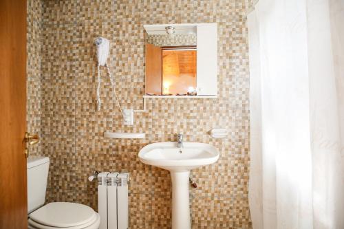 a bathroom with a sink and a toilet and a mirror at Patagonia Hostel in El Chalten