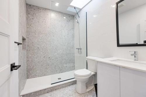 La salle de bains est pourvue d'une douche, de toilettes et d'un lavabo. dans l'établissement Modern & Bright 3BR with Sofabed in Mile-End, à Montréal