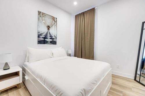 um quarto branco com uma cama e uma janela em Modern & Bright 3BR with Sofabed in Mile-End em Montreal