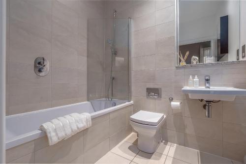 a bathroom with a tub and a toilet and a sink at Chic 1BR with Garden View in Central Bristol in Bristol