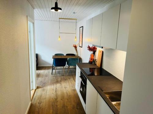 una cocina con armarios blancos y una mesa en una habitación en The Old Hotel Silkeborg - 1MTH, en Silkeborg