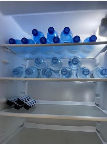 a refrigerator filled with lots of blue bottles at AirPort Apartment Chopina in Warsaw