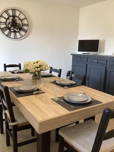 une table à manger avec des chaises et une horloge murale dans l'établissement La Casa d'Isabelle, Charme Corse à Patrimonio, à Patrimonio