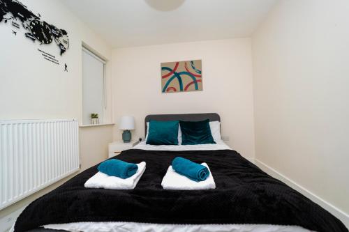 een slaapkamer met een groot bed met 2 blauwe kussens bij Stunning 4 bed house near stadium and green park in Reading