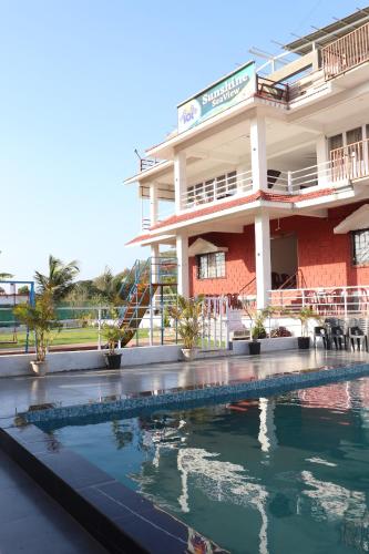 a building with a swimming pool in front of it at Sunshine Resort in Surai