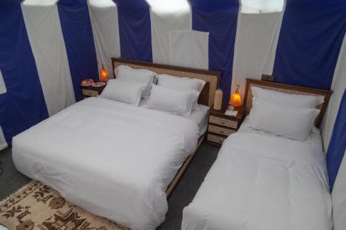 two beds sitting next to each other in a room at Four Season Camp in Merzouga