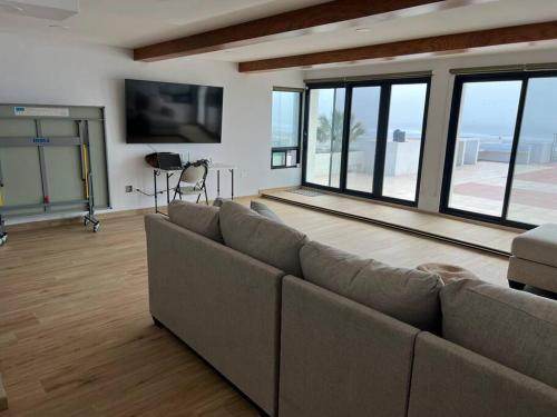 uma sala de estar com um sofá e janelas grandes em Oceanfront Home in Rosarito Beach em Santa Mónica Sur
