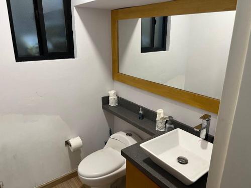 a bathroom with a toilet and a sink and a mirror at Oceanfront Home in Rosarito Beach in Santa Mónica Sur