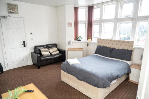a bedroom with a bed and a chair and windows at Bvapartments Deighton in Huddersfield