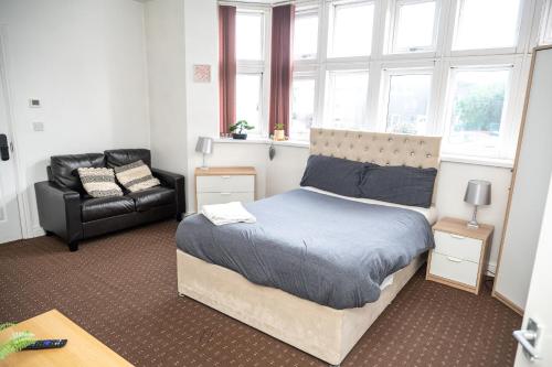 a bedroom with a bed and a chair and windows at Bvapartments Deighton in Huddersfield
