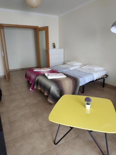 two beds in a room with a yellow table at Edifice Ibérico in Albufeira