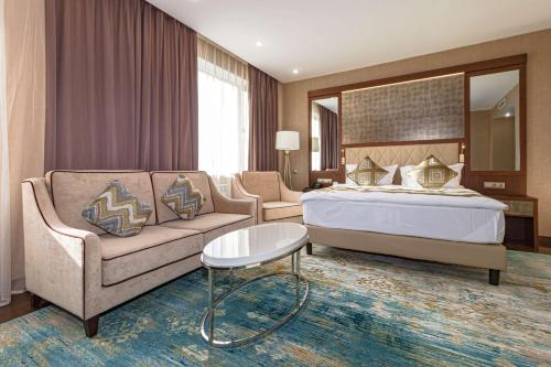 a hotel room with a bed and a couch at Best Western Plus Astana Hotel in Astana