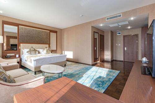 1 dormitorio con 1 cama y sala de estar en Best Western Plus Astana Hotel en Astaná