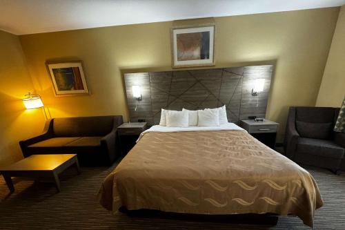 a hotel room with a bed and two chairs at Quality Inn near I-72 and Hwy 51 in Forsyth